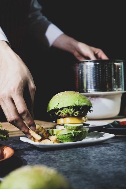 Green hamburger made by a cook on a black