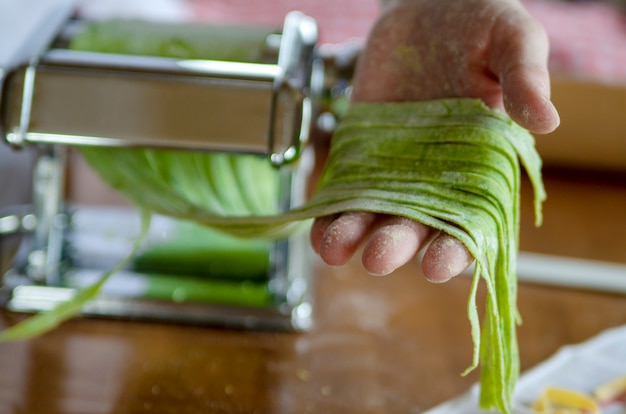 野菜で作った緑の手作りパスタヌードル、女性の手は新鮮なスパゲッティを握る