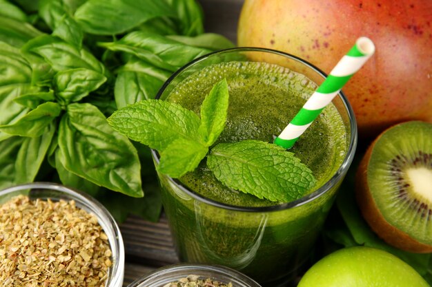 Green healthy juice with fruits and herbs on table