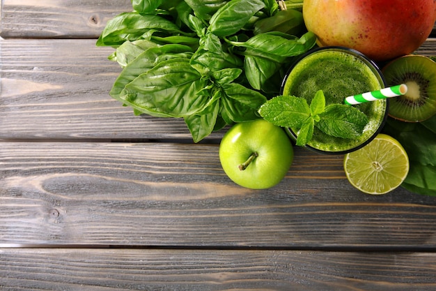 Foto succo verde sano con frutta ed erbe sulla tavola di legno da vicino