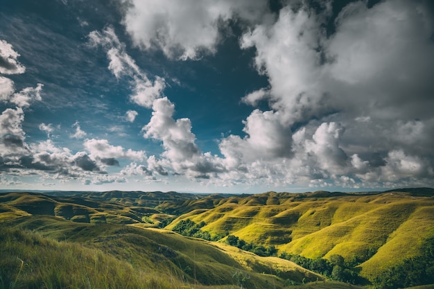 Green hills under blue cloudy sky view