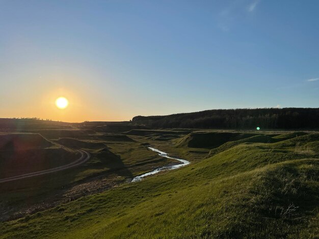 Green hills with a clear stream at sunset