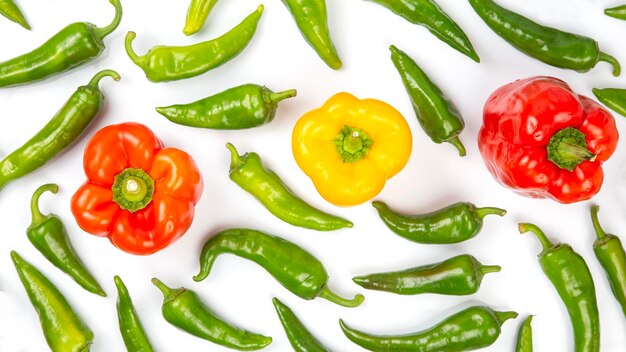 Green hot peppers and red and yellow bell peppers on a white background. vitamin vegetables for health