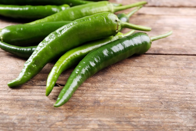 Green hot peppers on wooden table close up