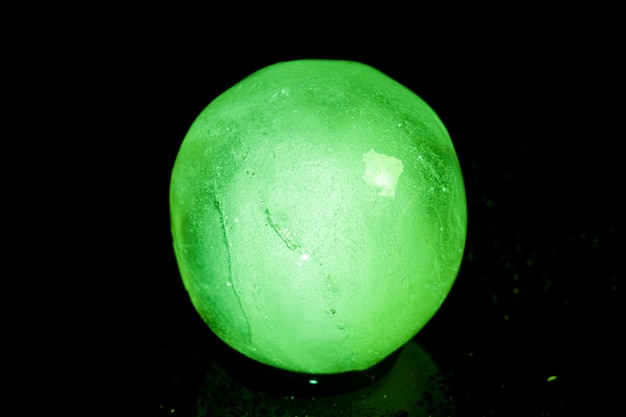 Green ice ball reflection on black background