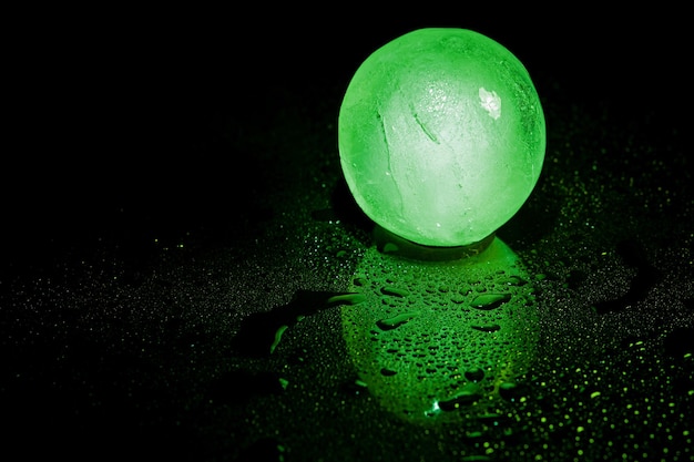 Green ice ball reflection on black background