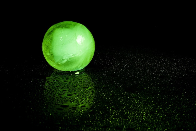 Фото Отражение зеленого ледяного шара на черном фоне