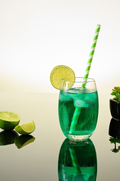 GREEN ICED DRINK DECORATED WITH LEMON ON A REFLECTIVE DARK BACKGROUND