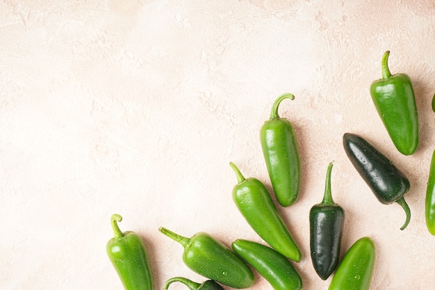 Green jalapeno peppers beige background, place for text. Top view.