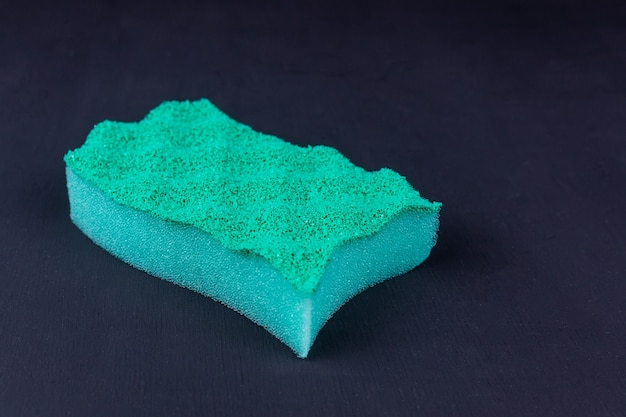 Green kitchen sponge on a black background in different poses.