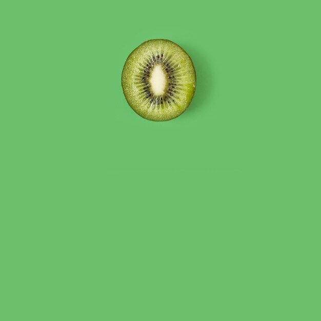 A green kiwi on a green background in a top view with copy space