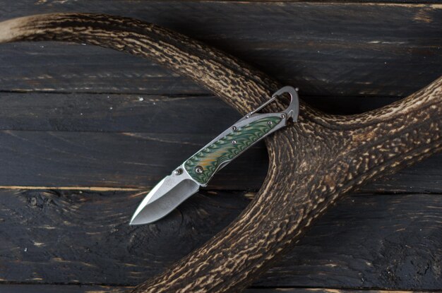 Photo green knife with a carabiner on a deer horn outdoor