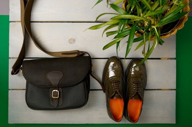 Green lacquered oxford shoes and crossbody bag on wooden