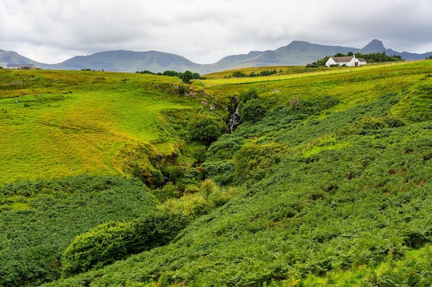 영국 스코틀랜드 스카이 섬의 높은 산과 오두막이 있는 녹색 풍경