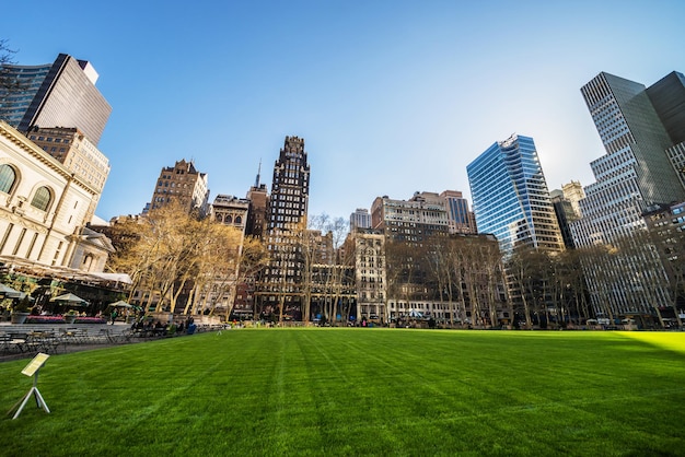 Foto prato verde e grattacieli in bryant park a midtown manhattan, new york, new york, stati uniti. turisti che si rilassano nel parco