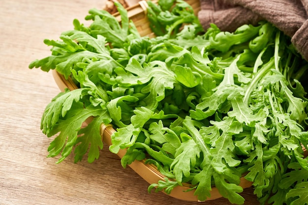 green leaves bunch crown daisy or garland chrysanthemum. glebionis coronaria in wood plate on wooden