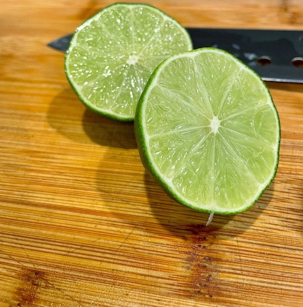 Foto limone verde tagliato a metà con un coltello su una tavola di legno