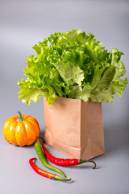 Green lettuce leaves in a paper ecological bag red pepper and pumpkin. Healthy lifestyle and nutrition