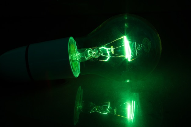 Green light bulb turned over on black background