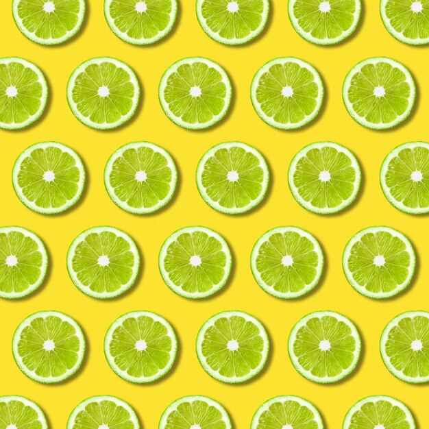 Photo green lime slices pattern on vibrant yellow color background