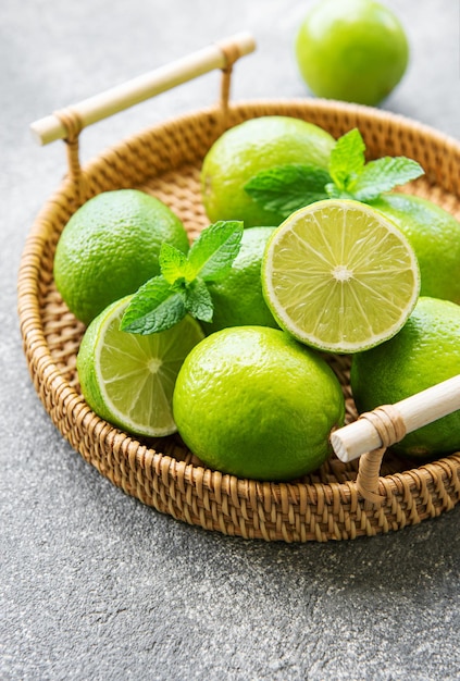 Limes verdi con foglie di menta fresca su vassoio di vimini