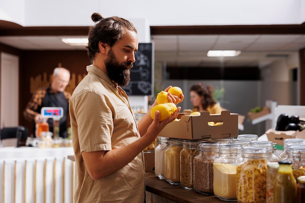 Green living man purchasing lemons grown by sustainable zero waste supermarket owner in his garden. Customer happy to find eco friendly pesticides free fresh fruits in local neighborhood store