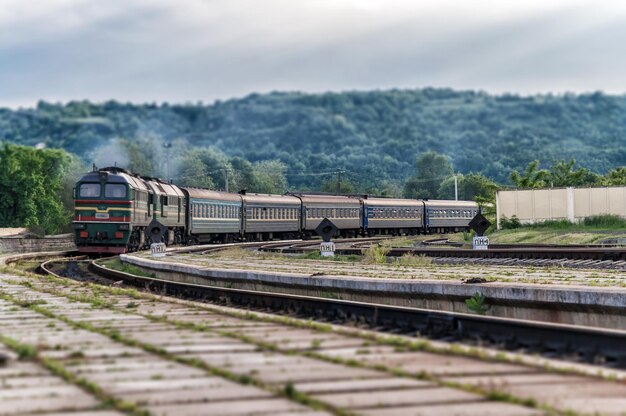 Green Locomotive arrives at a small station among the green mountains in the Ternopil region Ukraine Effect tiltshifted perspective