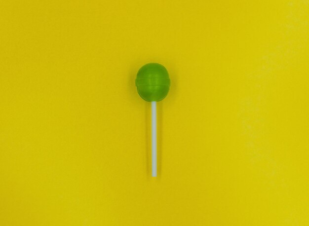 Green lollipop on a yellow background