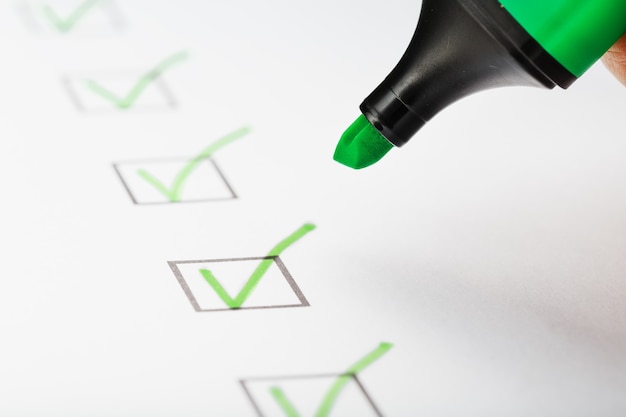 Foto pennarello verde con pennarelli sul foglio della lista di controllo. elenco di controllo completato il concetto di attività.