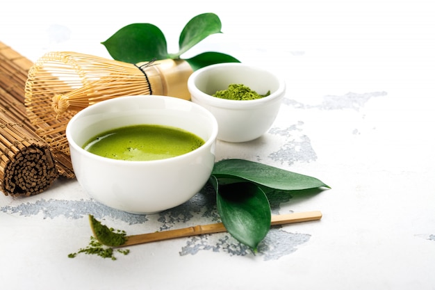 Green matcha tea drink and tea accessories on white background