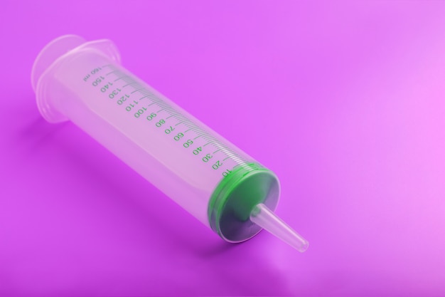 Green medical syringe on lilac surface