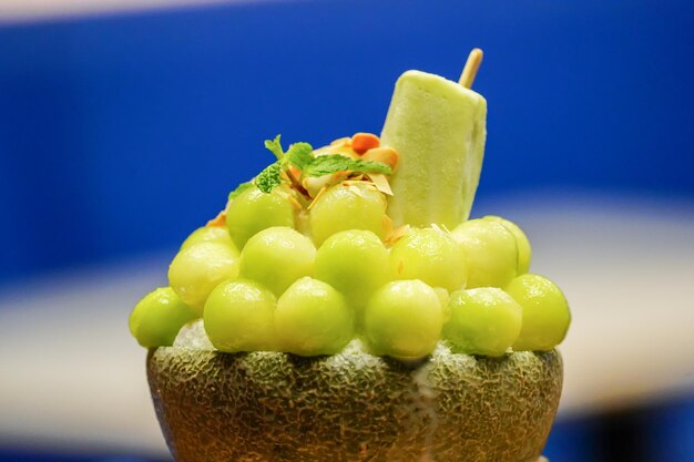 Photo green melon with ball shape are arranged on the top of bingsu korean icecream style and decorated with green tea icecream and mint leaf