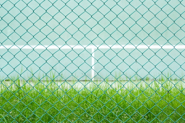 Green metal cage front the green tennis court and wall for practice