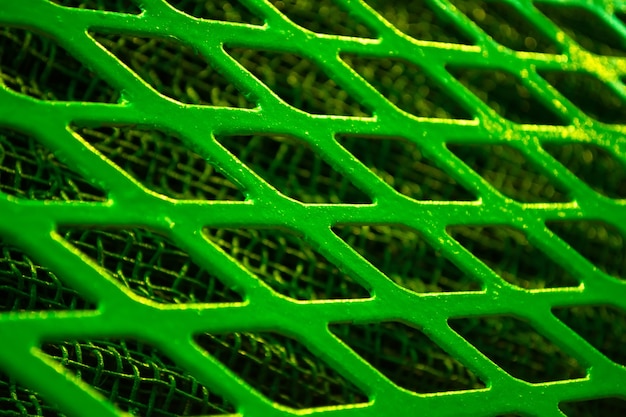 Photo green metal lattice lozenge rhombus close-up, under a fine metal grid.