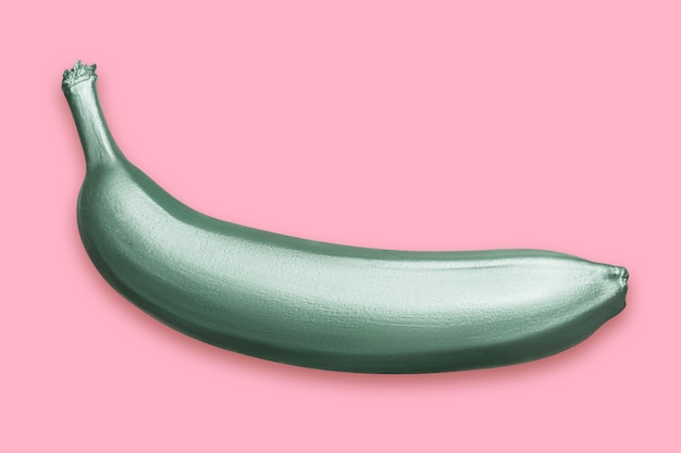 Green metallic banana on a pink background A modern creative concept