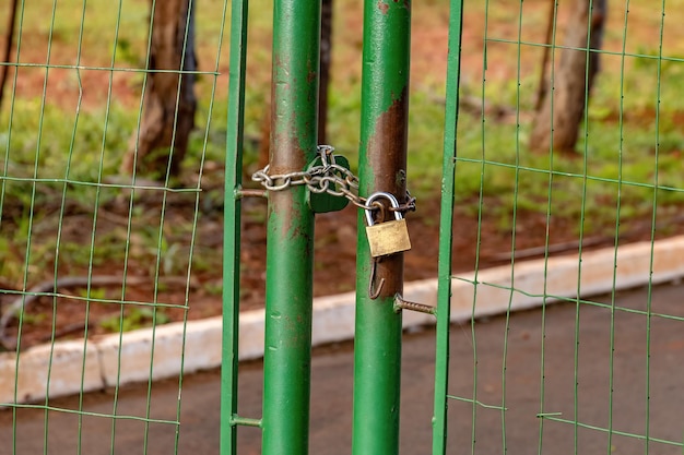 Green metallic gate locked by a chain with a padloc