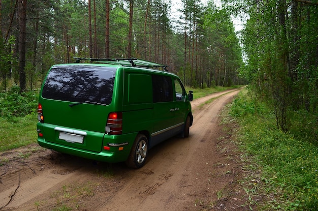 A green minibus on a dirt road in the forest