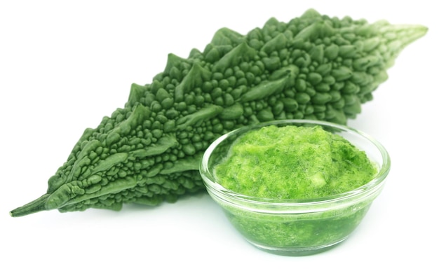 Green momodica with paste in a glass bowl over white background