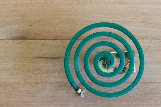 Foto bruciore di repellente per zanzare verde e fumo bianco su un tavolo di legno con luce sfocata verde
