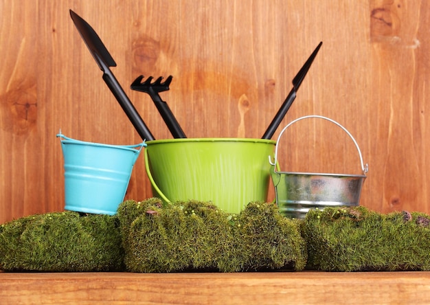 Foto muschio verde e secchio con attrezzi da giardinaggio su sfondo di legno