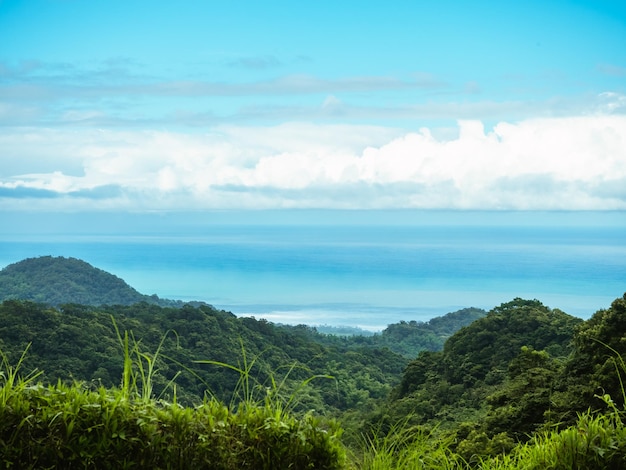 Foto montagna verde e cielo nuvoloso blu con il mare