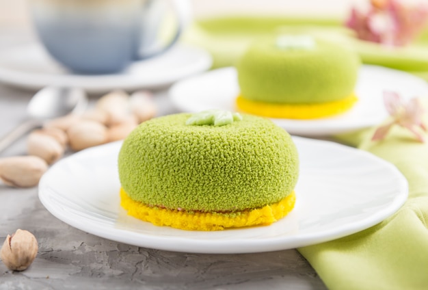 Green mousse cake with pistachio cream and a cup of coffee. side view