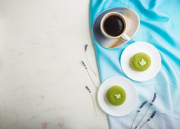 Green mousse cake with pistachio cream and a cup of coffee. top view, copyspace.