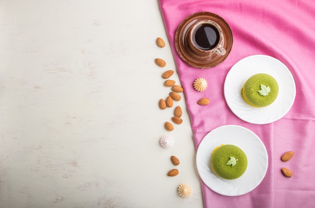 Green mousse cake with pistachio cream and a cup of coffee. top view, copyspace.