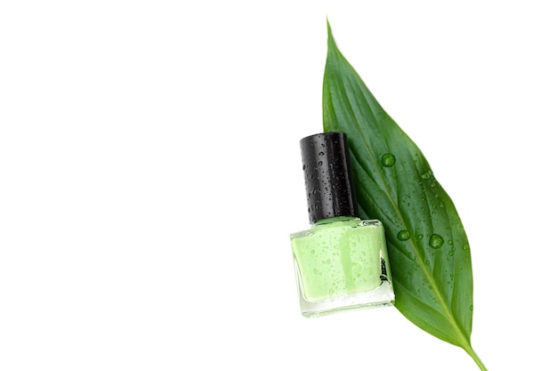 Green nail polish bottle on white surface.