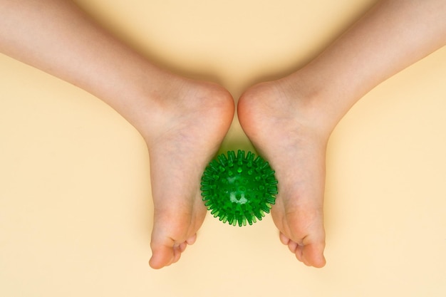 Green needle ball for massage and physiotherapy on a beige background with the image of a childs