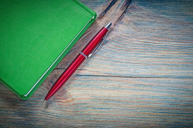 Green notepad pen on vintage wooden board education concept