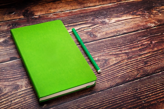 Green Notepad with a felt-tip pen on a brown wooden table, top view.