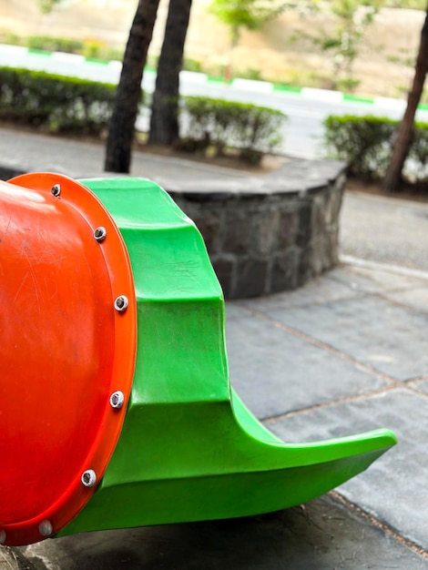 A green object with a red handle is sitting on a stone bench.