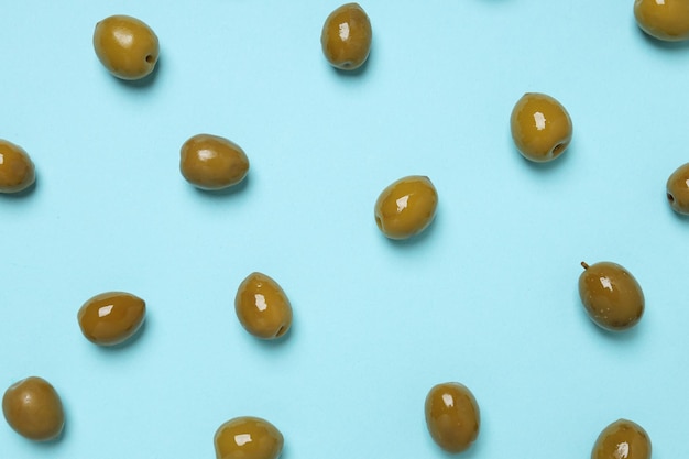 Green olives on blue background top view